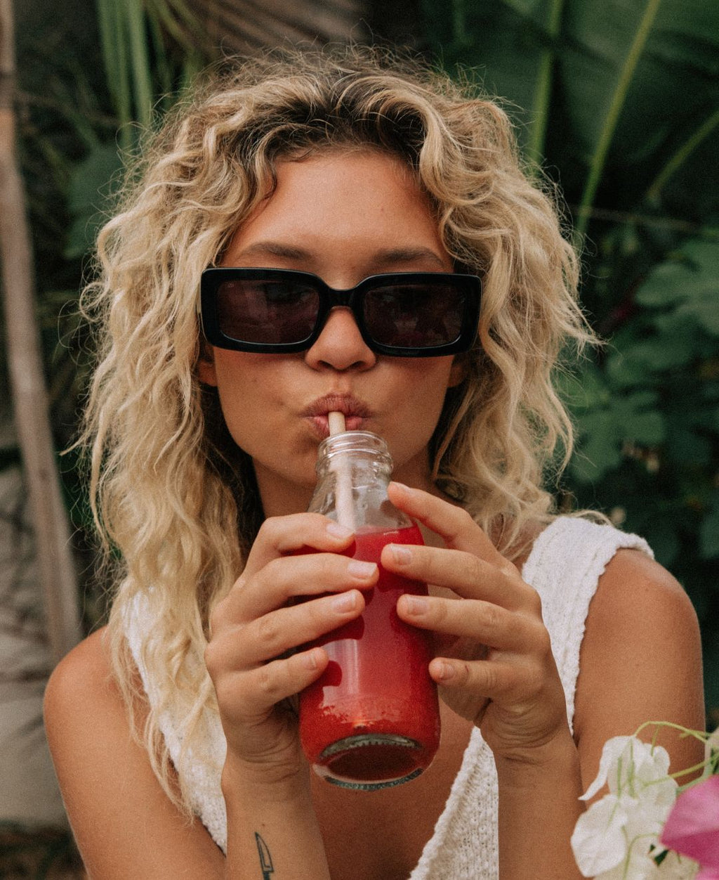 Women wearing black rectangle women's Sito Shades sunglasses sipping on a juice.