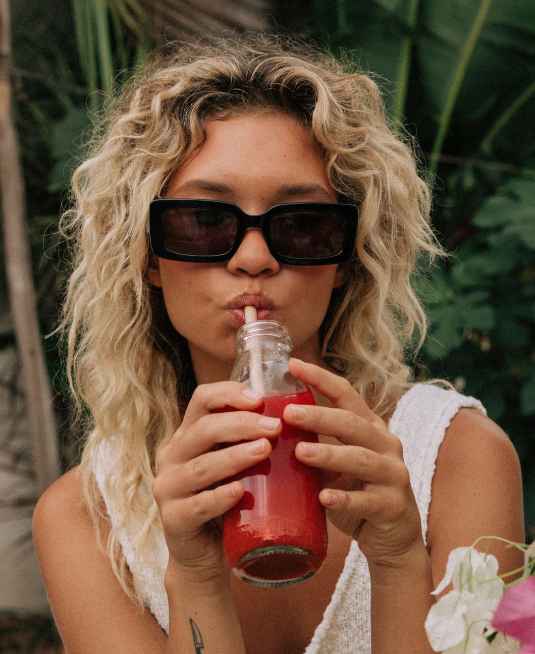 Women wearing black rectangle women's Sito Shades sunglasses sipping on a juice.