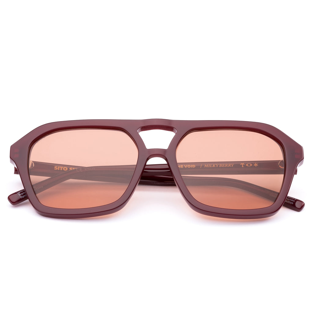 Dark red aviator sunglasses with candy coloured lenses on white background