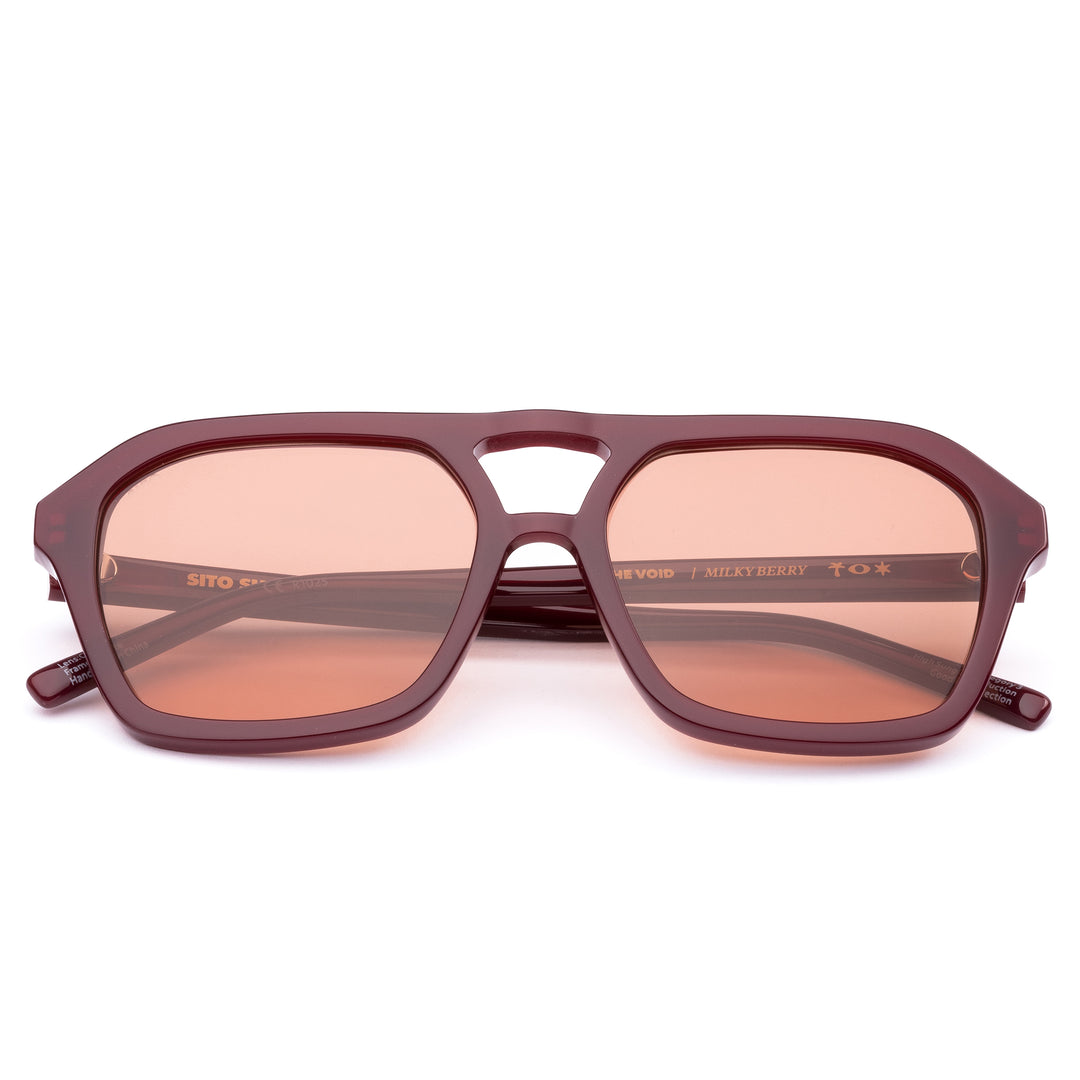 Dark red aviator sunglasses with candy coloured lenses on white background