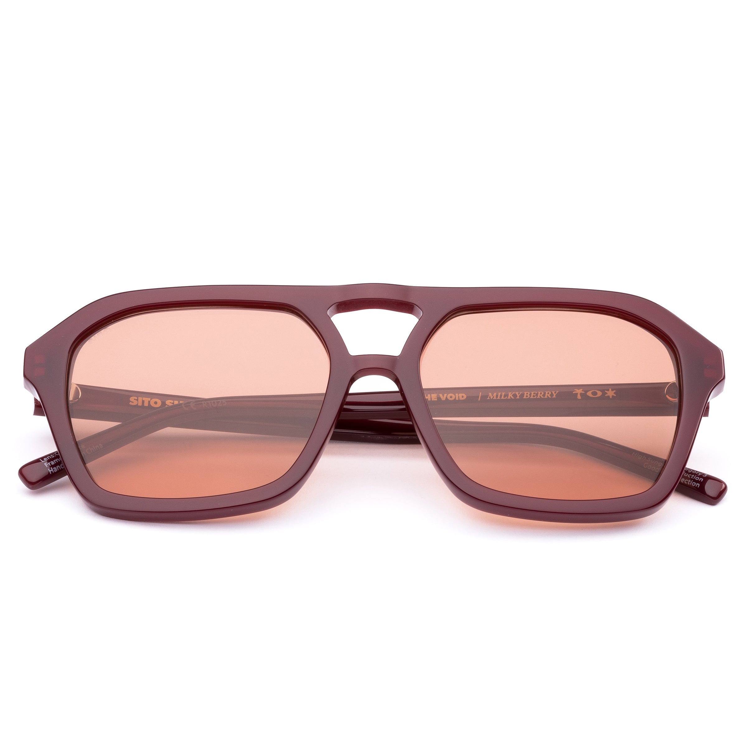 Dark red aviator sunglasses with candy coloured lenses on white background